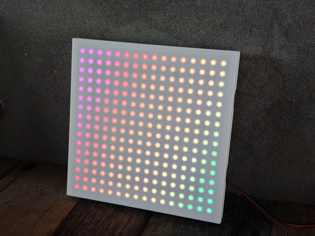 Matrice LED allumée en dégradé de couleurs derrière un panneau blanc